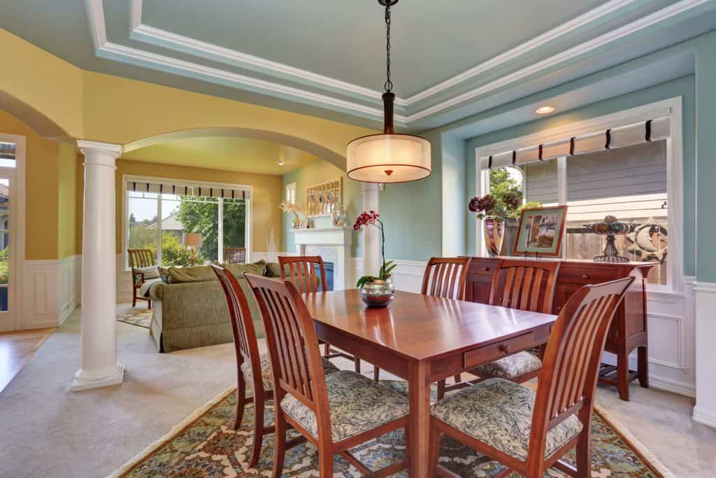 Combinaison brillante de cuisine et de salon à aire ouverte jaune et bleu clair avec des chaises en bois foncé