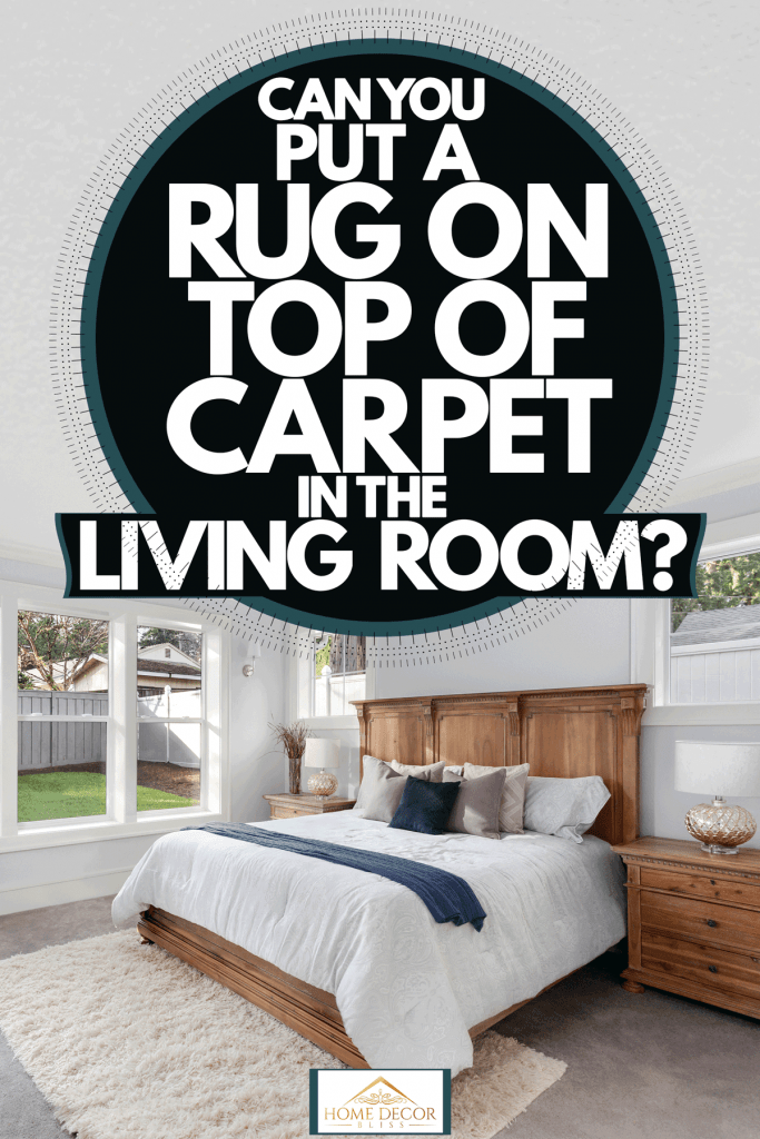 Interior of a modern bedroom with white painted walls, a huge wooden bed with white beddings, and a carpeted flooring with a beige area rug, Can You Put A Rug On Top Of Carpet In The Living Room?