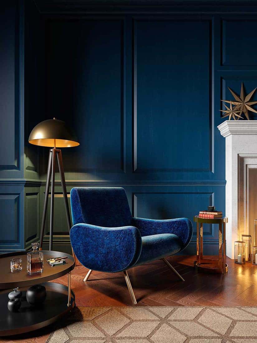 Classic royal blue color interior with armchair, fireplace, candle and floor lamp
