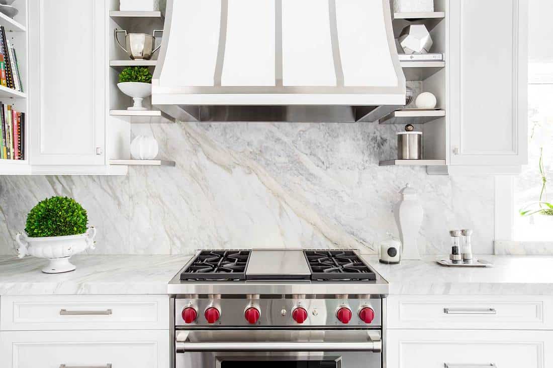 Classic white kitchen with gas range and marble backsplash