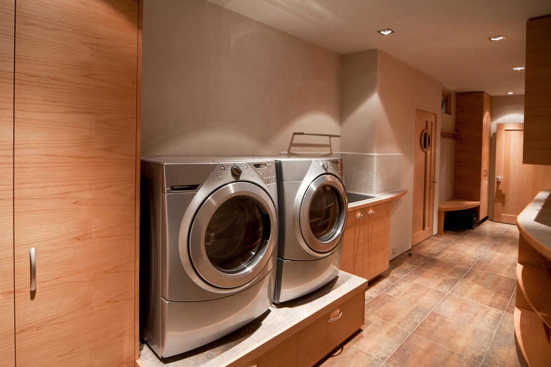 Close up of a front loader washer and dryer in caramel brown pain laundry room, 15 Great Laundry Room Wall Paint Ideas