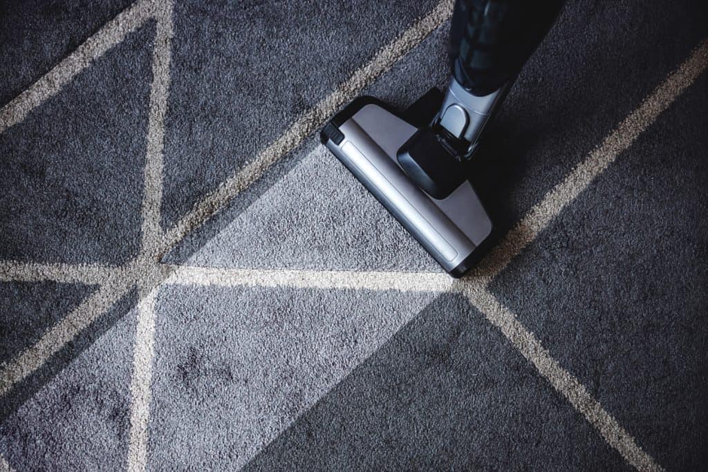 Close up of steam cleaner cleaning very dirty carpet or rug in the living room