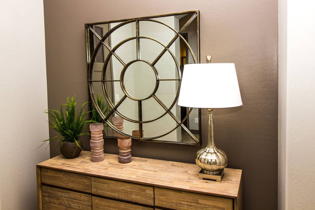 Contemporary Wall Mirror Over Wooden Bedroom Dresser With Lamp & Decorator Items