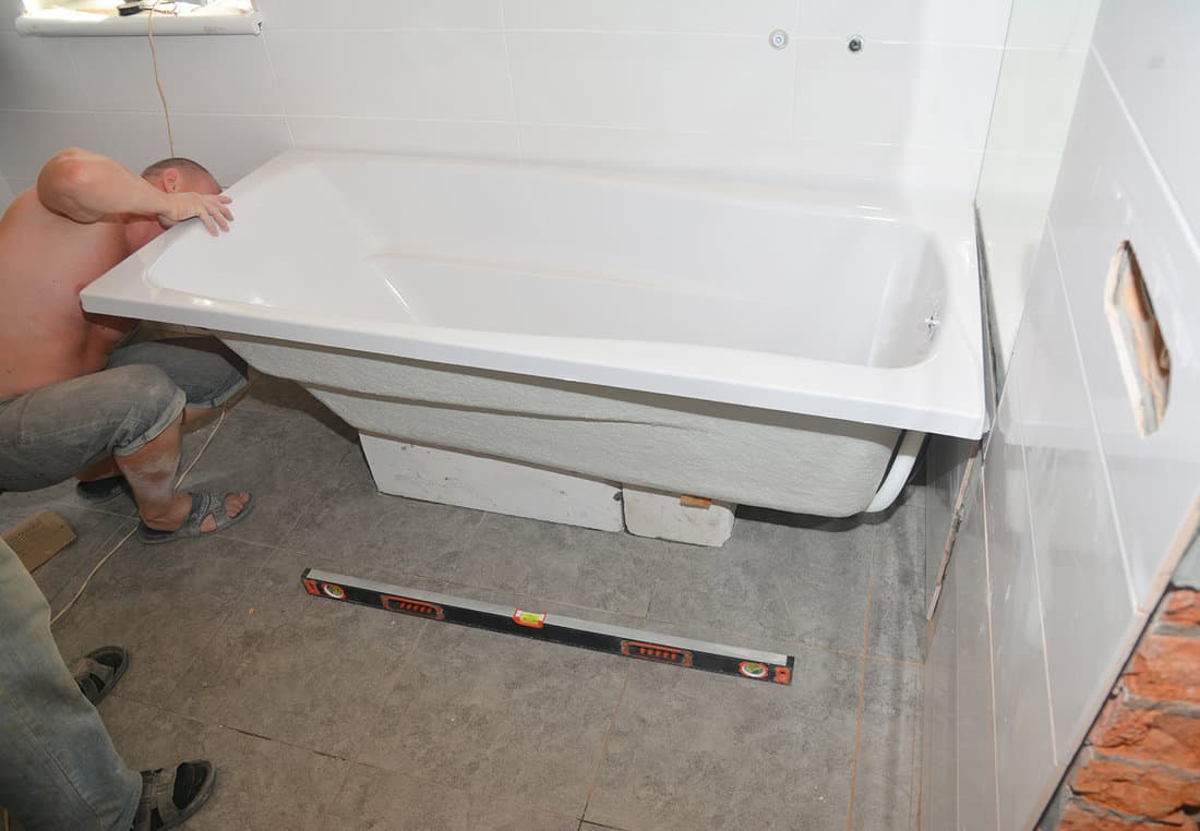 Contractors installing bathtub in house bath room