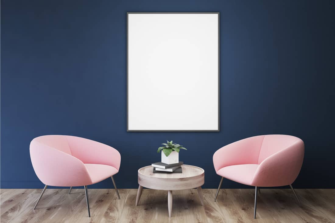 Empty blue room, pink armchairs, table, poster. Pair Pale Pink With Bold Navy Walls