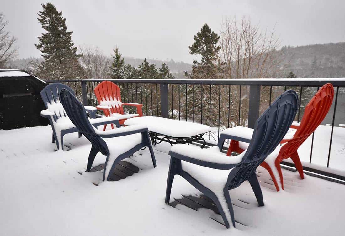 Falling snow on chairs and table on wooden deck