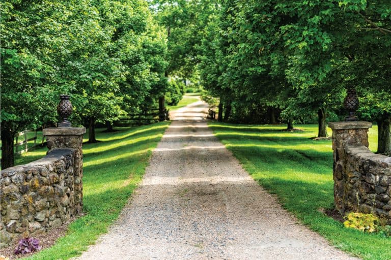 Gated open entrance with road driveway in rural countryside in Virginia estate with stone fence and gravel dirt path street with green lush trees in summer. Create A Formal Entrance For Your Gravel Drive