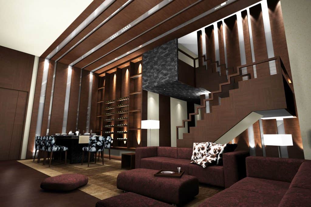 Huge interior of a modern living room with white accent wall, brown decorative panels stretching to the ceiling and red velvet colored sectional sofas