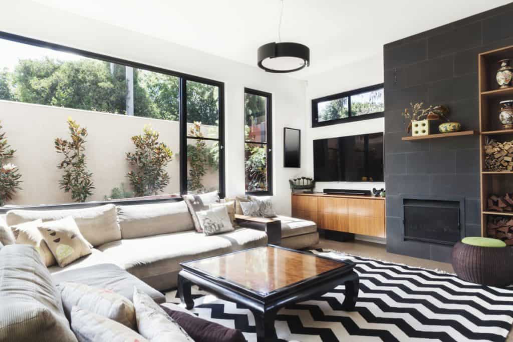 Interior of a bright modern living room with white painted walls, black and white tiles, and a long sectional sofa