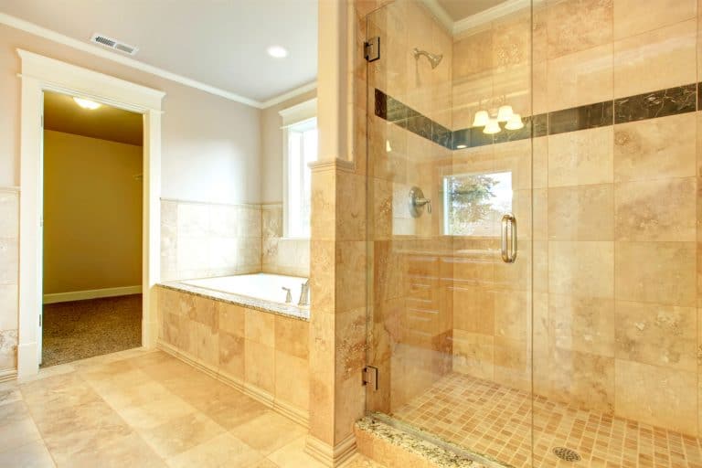 Interior of a luxurious bathroom with white painted walls, glass walled shower area, and beige decorative shower wall, Should Bathtub Tile Go To The Ceiling?