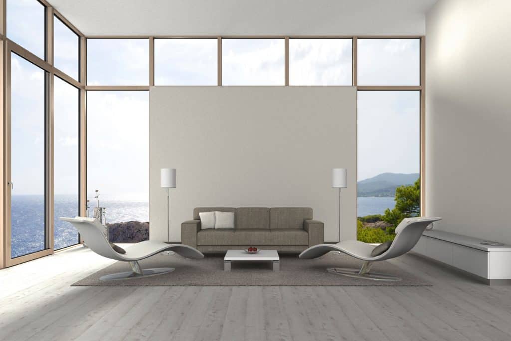 Interior of an ultra modern contemporary living room with white painted walls, curved relaxing chairs, and a gray square armed sofa