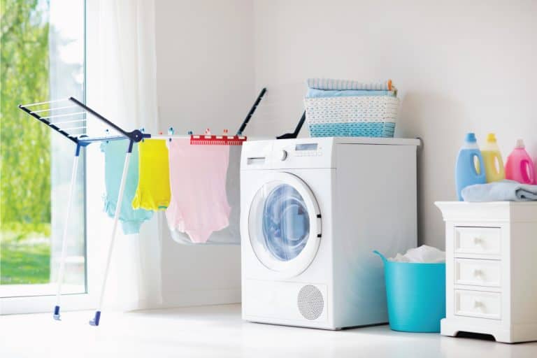 Laundry room with washing machine or tumble dryer. Modern household devices in white sunny home. Clean washed clothes on drying rack. Liquid washing detergent in plastic bottle and fabric softener. 15 Wonderful White Laundry Room Ideas