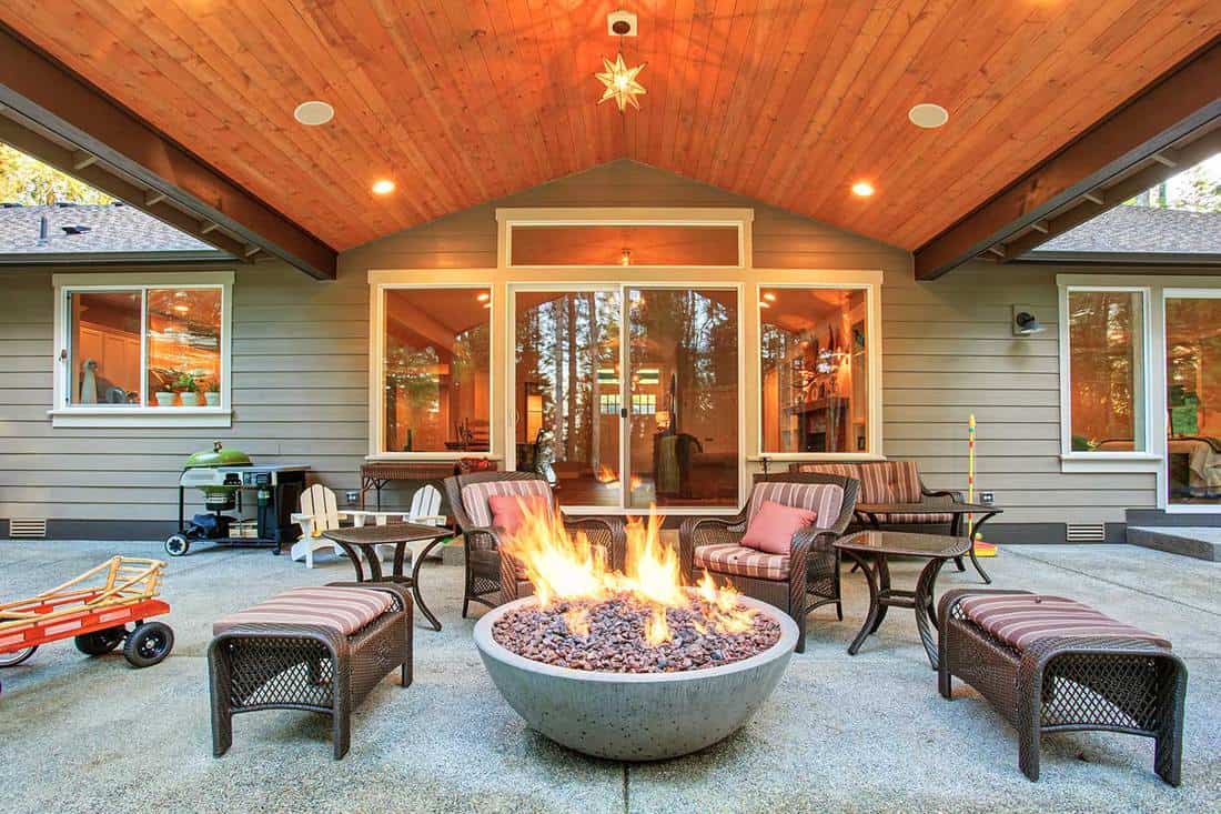Large backyard with grass and covered patio with fire pit