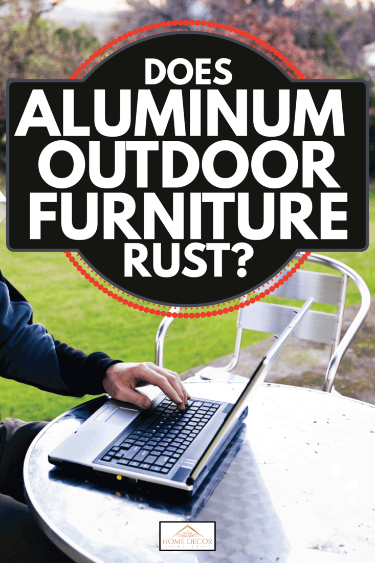 Man in casual clothes working on a laptop in an idyllic country garden with aluminum outdoor furniture. Does Aluminum Outdoor Furniture Rust