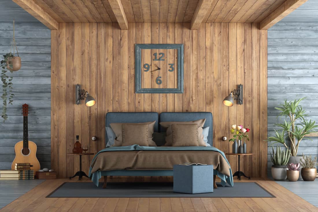 Master bedroom in rustic style with blue double bedroom against wooden paneling and real potted plants