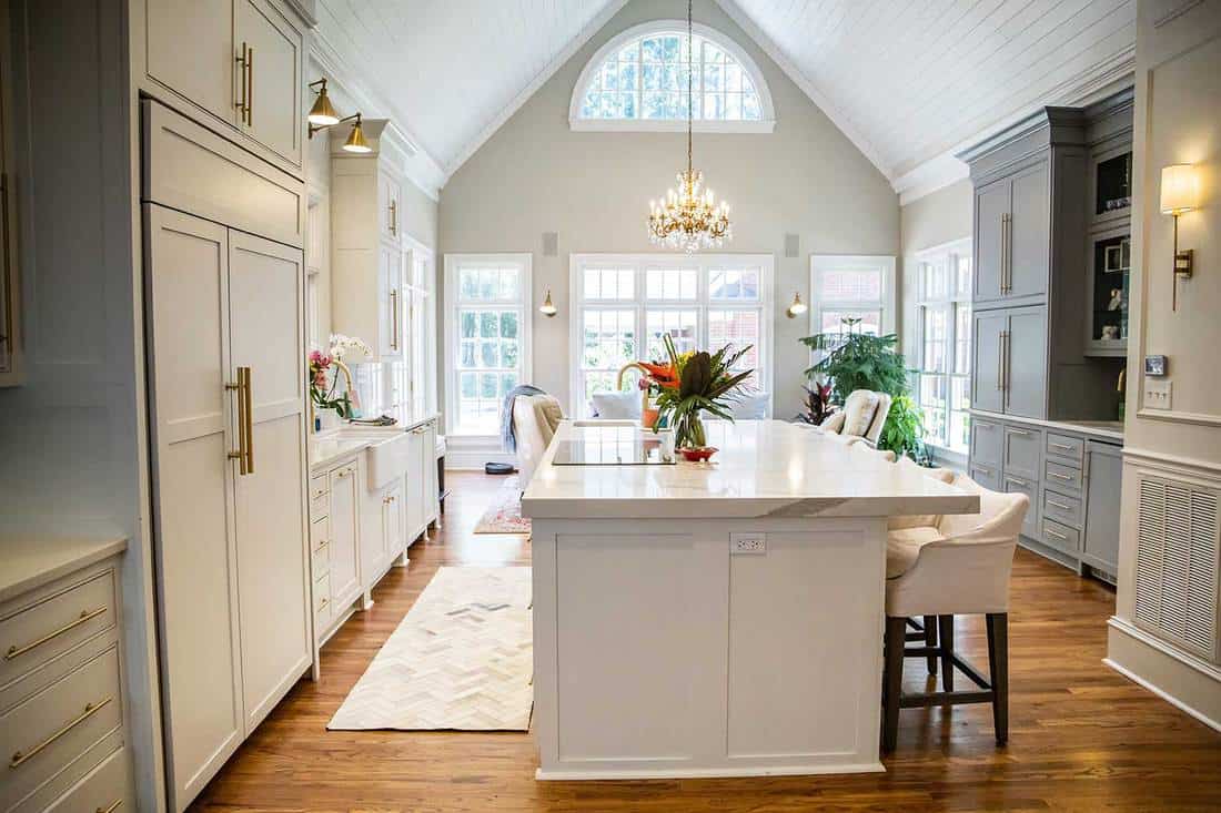 Open concept elegant and spacious kitchen with marble countertops, chandelier, and two-toned cabinets