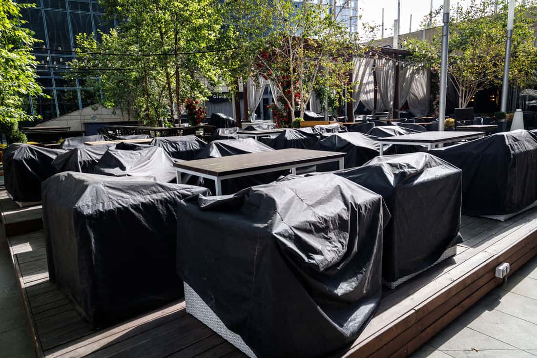 Outdoor cafe with furniture covered with rain covers. Preparing a street cafe for the season