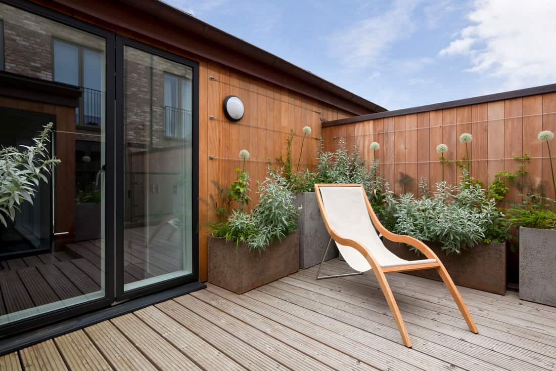 Simple attractive modern urban balcony garden with potted plants and reclining chair, What Are The Best Types Of Wood For Outdoor Furniture?
