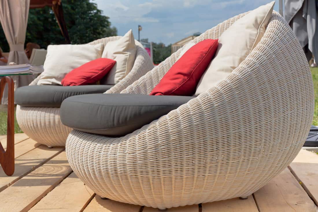 Soft wicker armchairs with color pillows outdoors. Horizontal shot