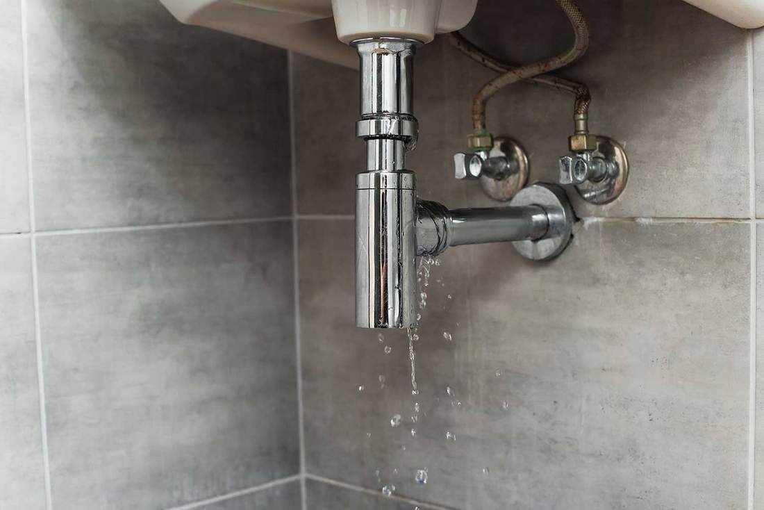 Steel pipes with water drops on gray tile bathroom