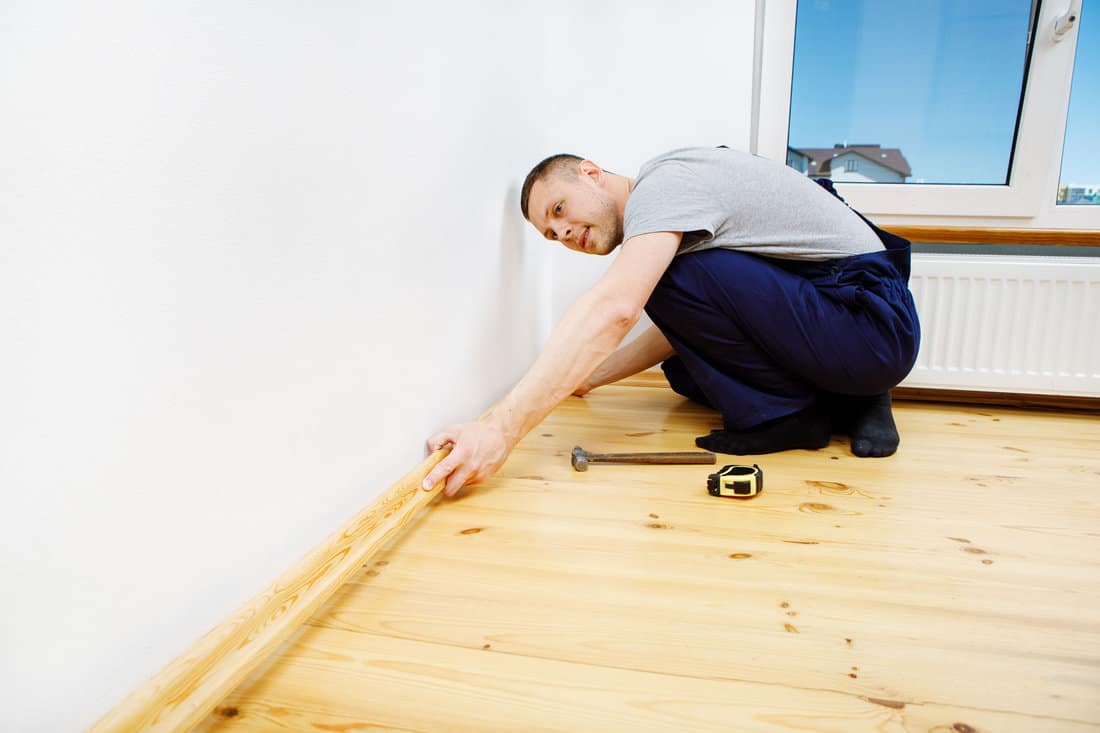 To make repairs. Installing a new skirting board. a man makes repairs in a room 