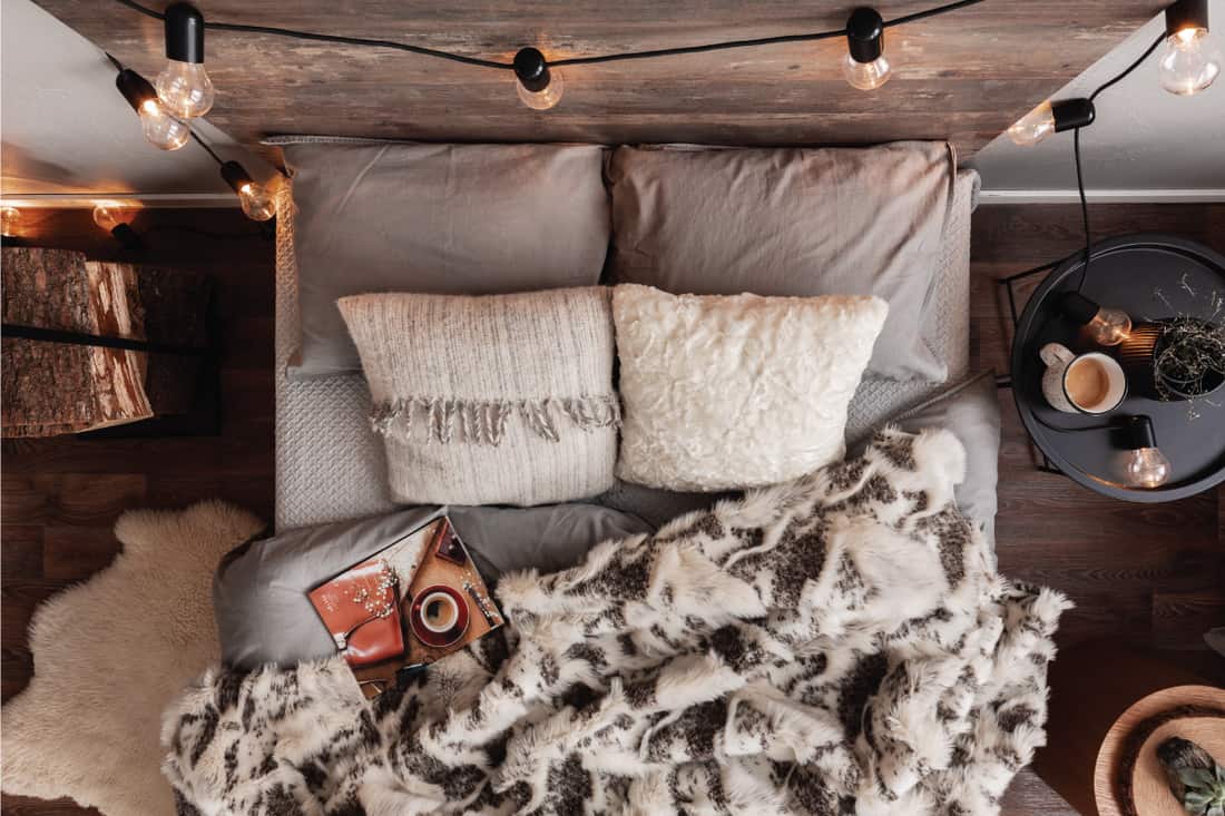 Top view of unmade bed with pillows, warm blanket and magazine. 15 Rustic Bedroom Ideas On A Budget