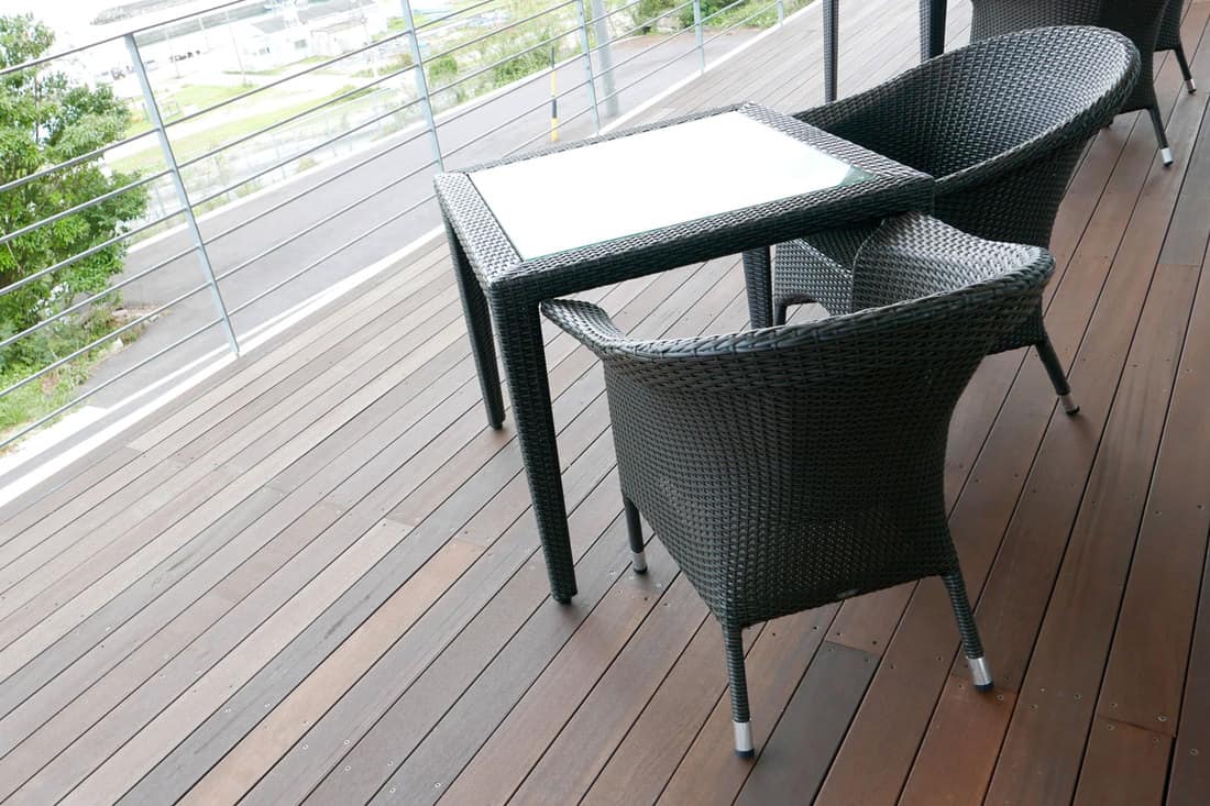 Two plastic outdoor dining chairs and table outside a wooden flooring patio
