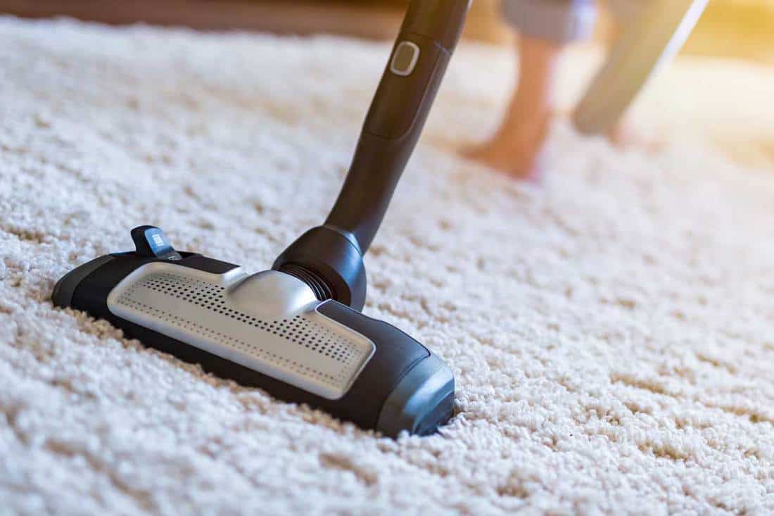 Woman using a vacuum cleaner while cleaning carpet in the house, How Do You Make Carpet Or A Rug Fluffy Again?