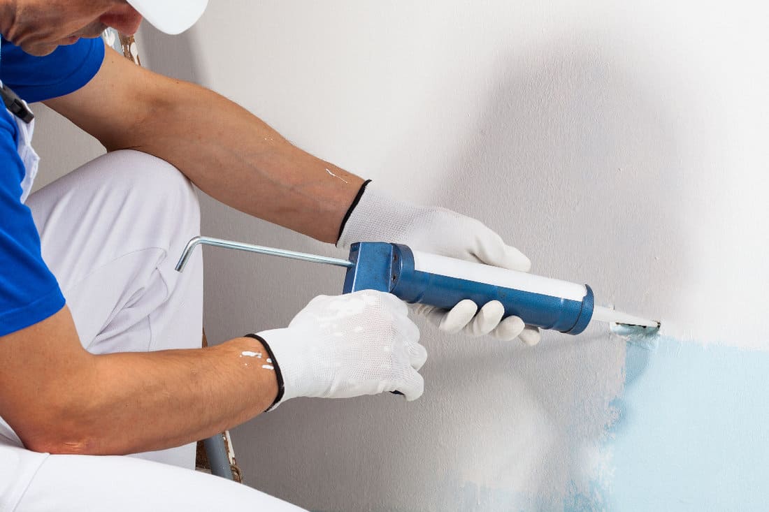 Worker applying silicone sealant on the wall