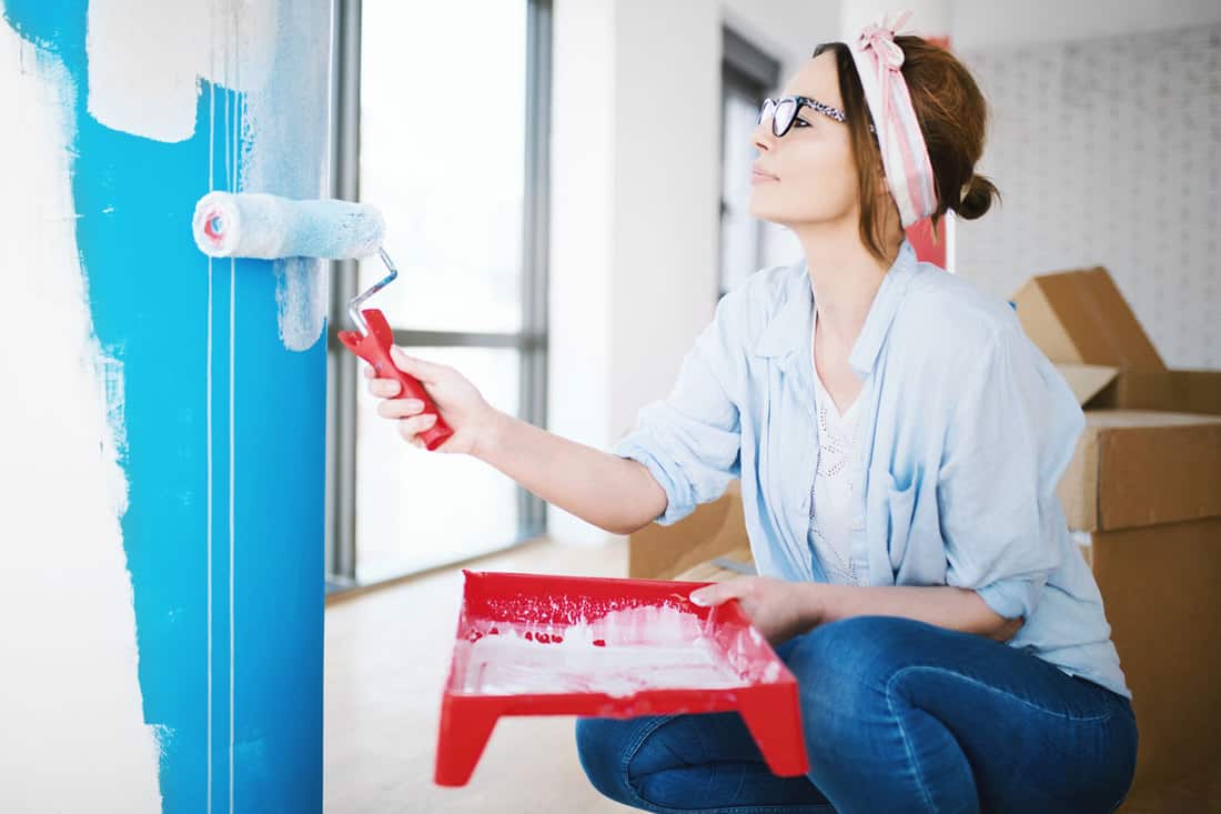 Young woman painting wall, enjoying her home renovation