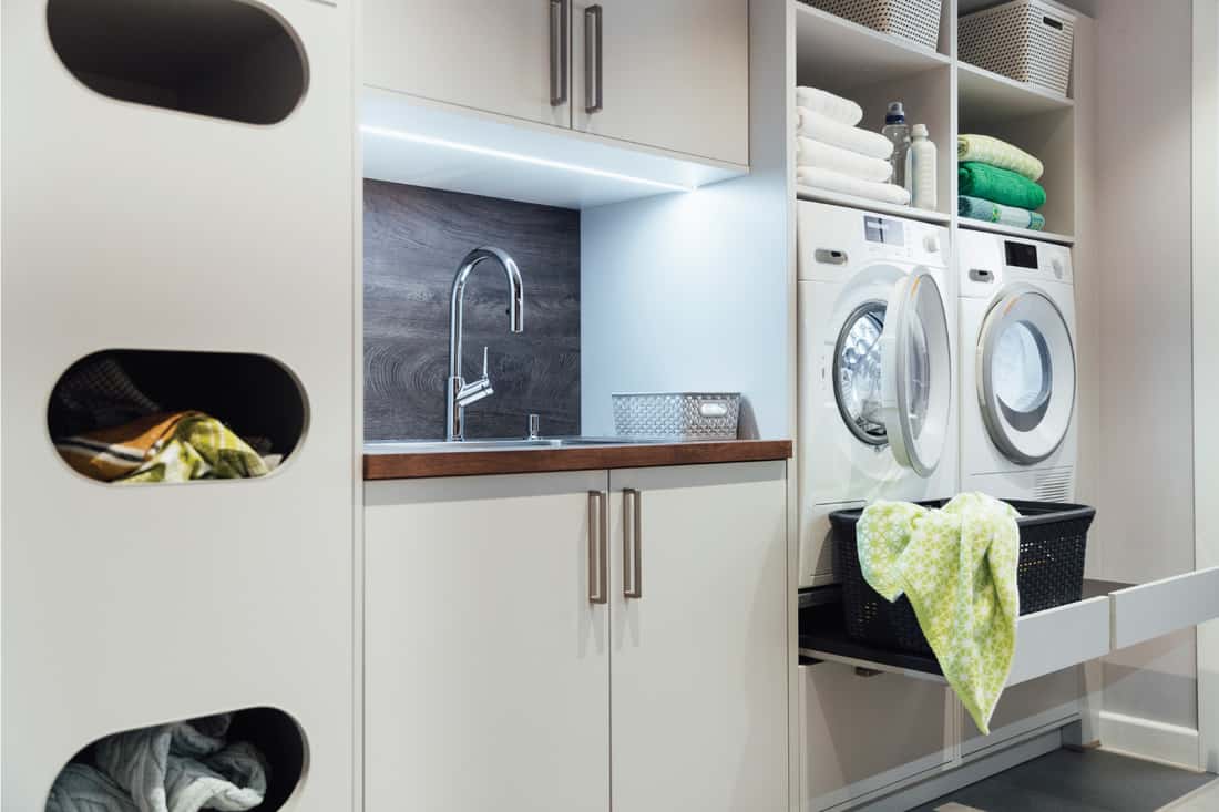 cuisine utilitaire vide ultra moderne qui dispose d'une machine à laver et d'un sèche-linge ainsi que d'un évier, le tout intelligemment intégré dans le design intérieur.