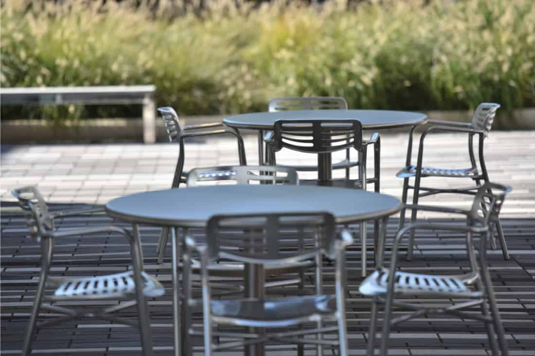 unoccupied outdoor aluminum tables and chairs under the shade. Does Aluminum Outdoor Furniture Rust