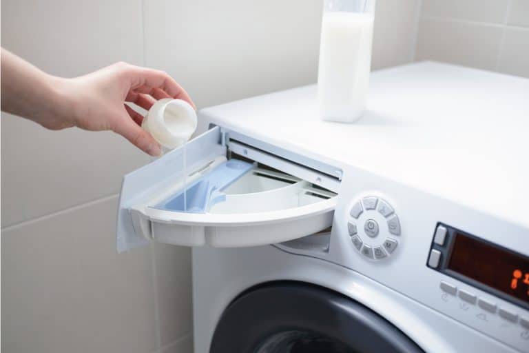 woman's hand pouring white liquid fabric softener on a automatic washing machine tray. 3 Types Of Fabric Softeners To Know