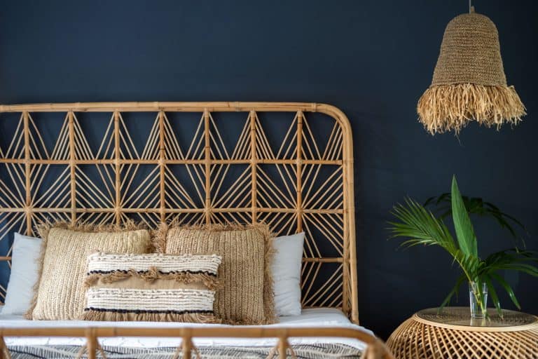 A Rattan bed with gorgeous boho themed and a wicker end table with a plant on top, 15 Great Rattan And Wicker Furniture Ideas [By Room]