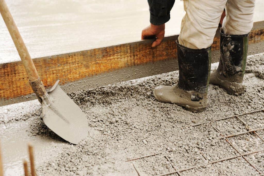 A construction worker leveling a concrete slab