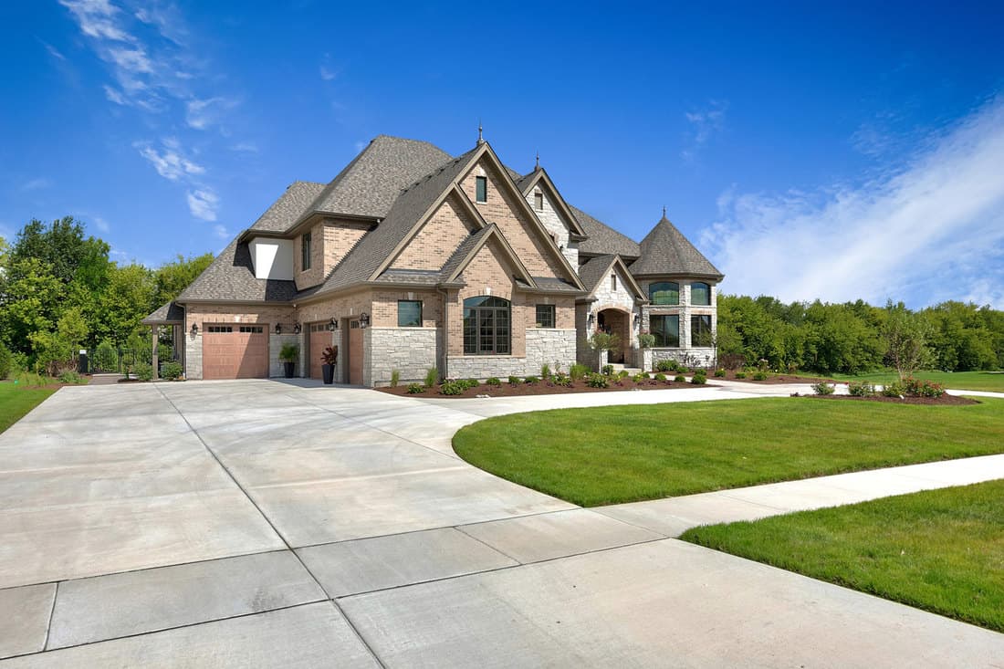 A huge mansion located on the plain filed with a huge driveway photographed on a sunny day, Does A Driveway Need Rebar?