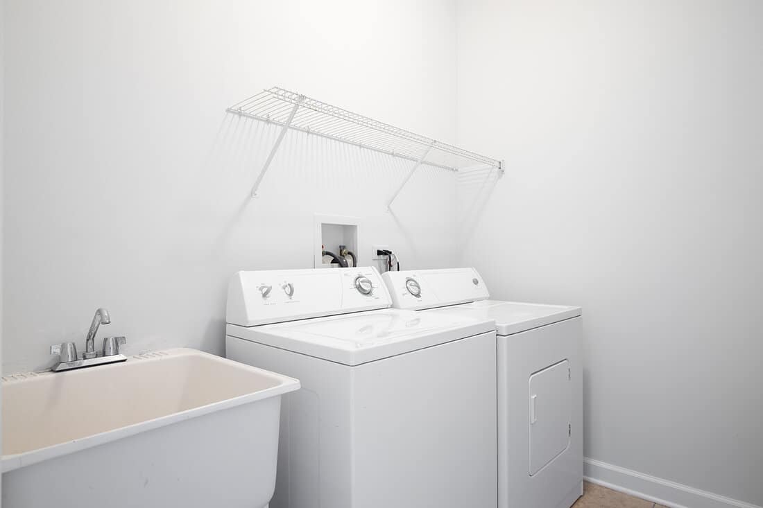 A laundry room with a utility sink and white washer and dryer appliances