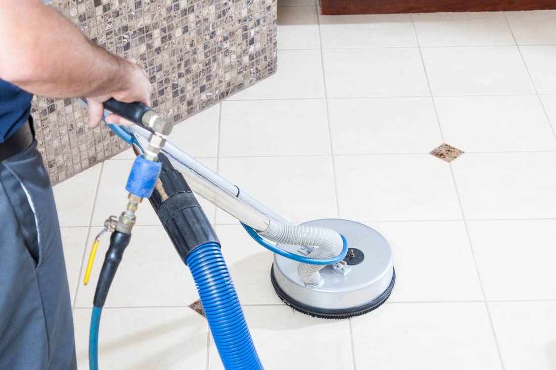 A man cleaning the bathroom floor with an electric floor cleaner, 7 Steps To Clean A Bathroom Floor With Bleach