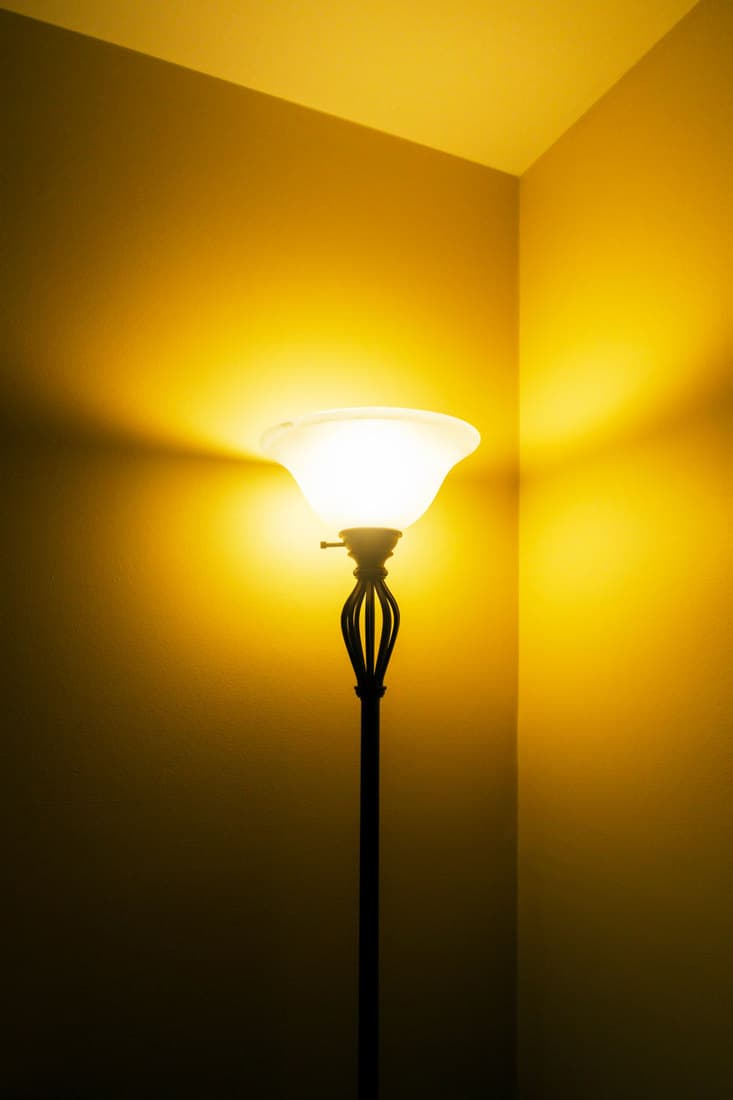 A tall floor lamp glowing on the side of a room