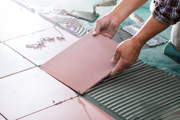 A tile setter placing pink ceramic tiles inside the living room, What Kind Of Paint Do You Use When Painting Ceramic Tile Floors?