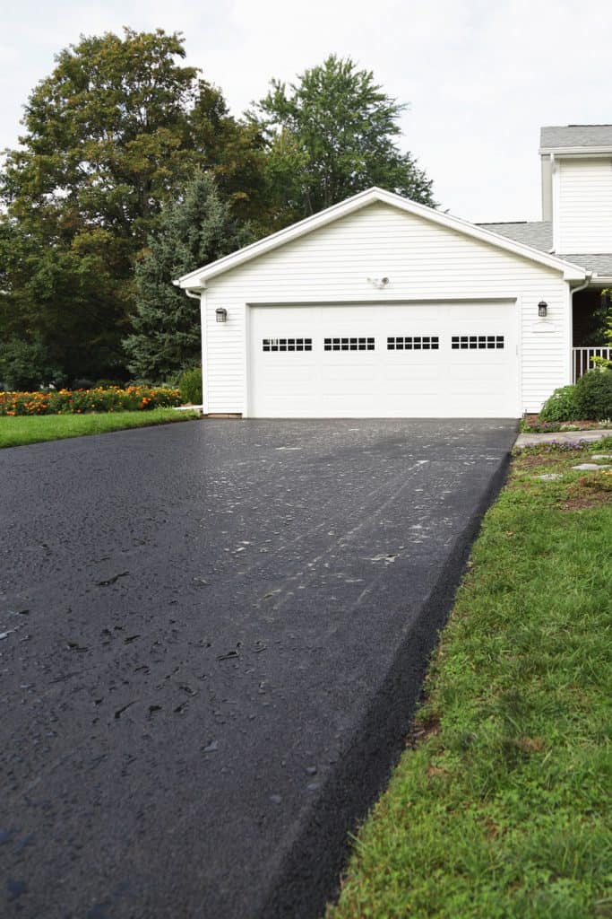 A white painted garage door with an asphalt driveway