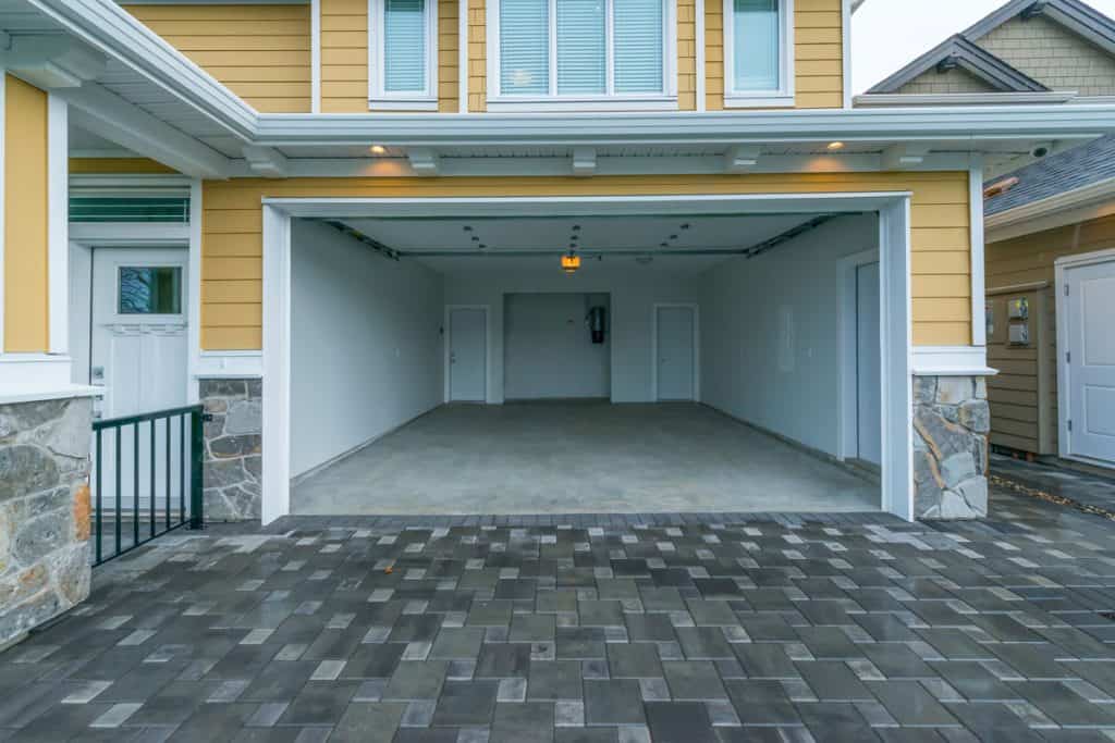 A yellow siding house with white trims and an opened garage