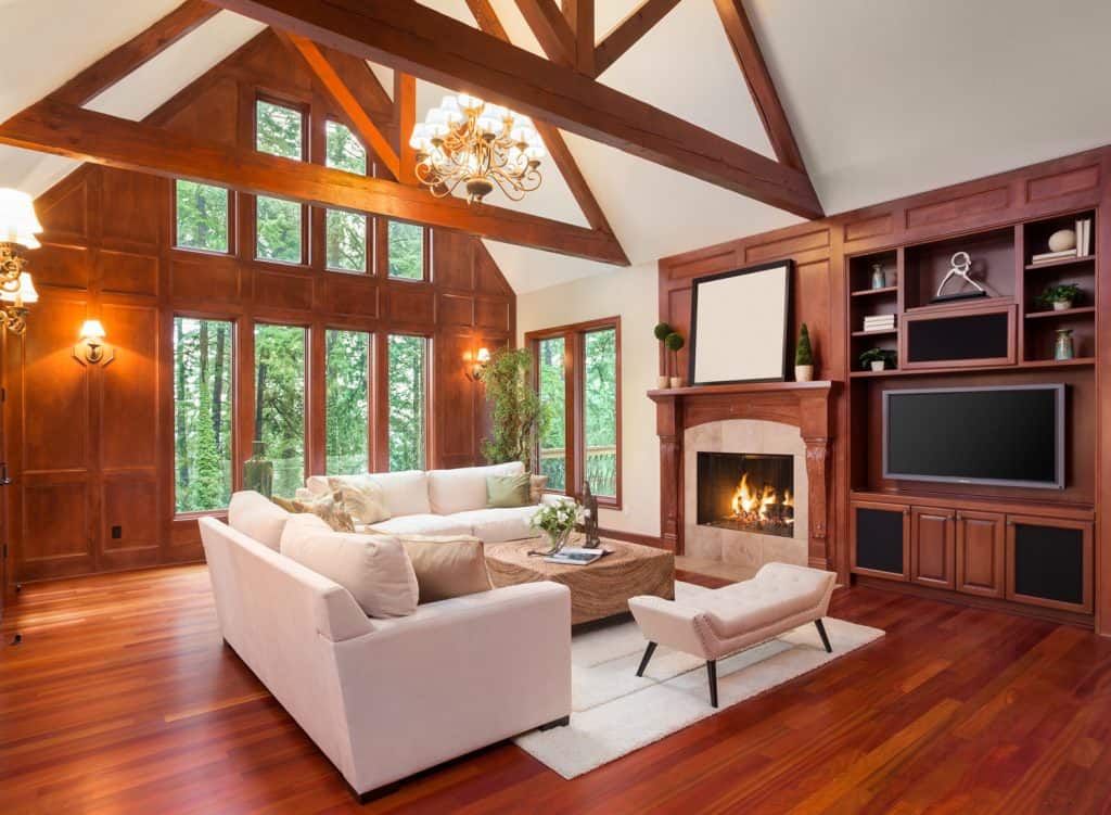 Bel intérieur de salon avec planchers de bois franc et cheminée dans une nouvelle maison de luxe.  Comprend des encastrés avec télévision et des plafonds voûtés.