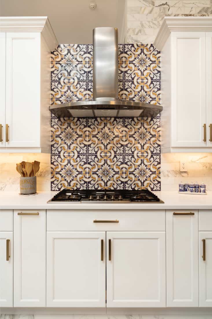 Beautiful luxury home kitchen with white cabinets and patterned backsplash