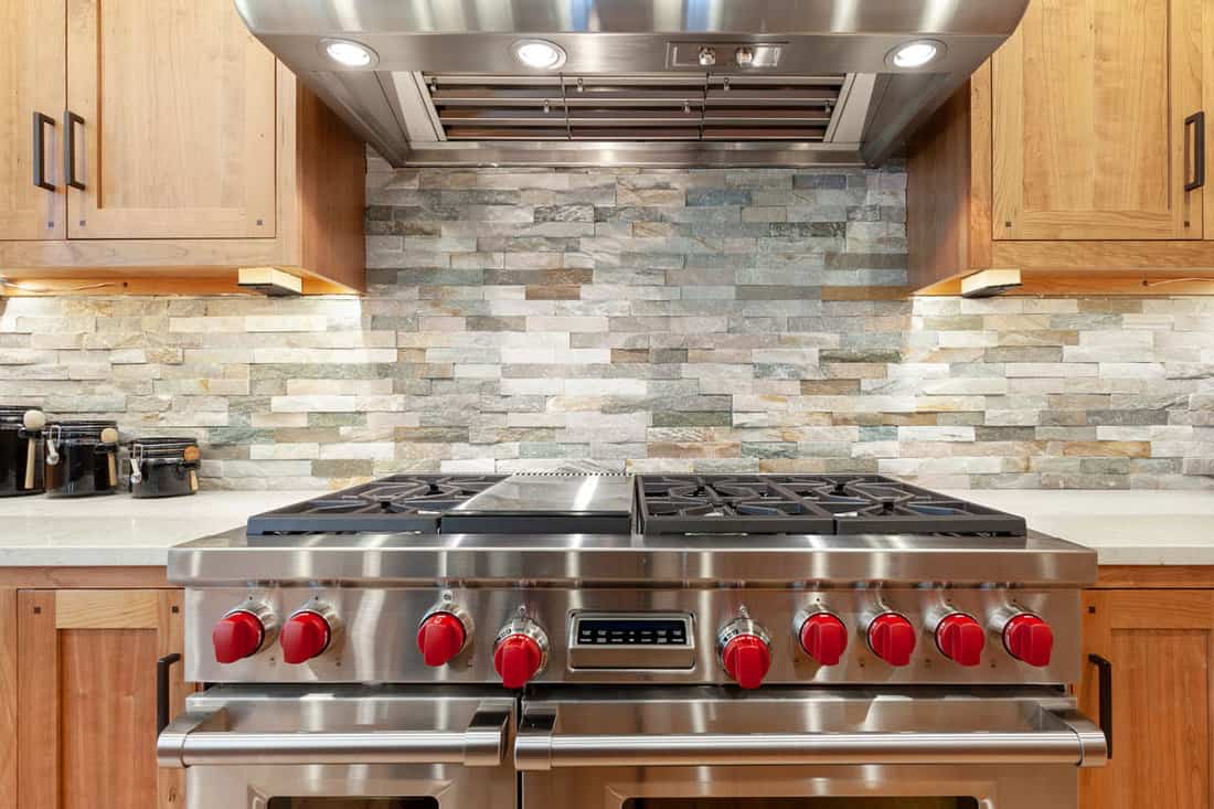 Brick tiled backsplash kitchen with wooden cabinets and white backsplash