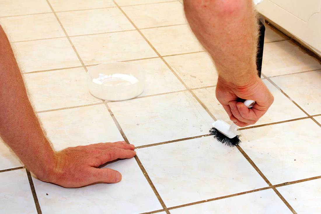 Cleaning grout from tiled floor using brush