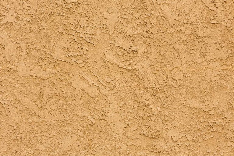 Close-up of a textured Stucco wall, Can New Stucco Get Wet? [And How To Repair Water Damage When It Happens]