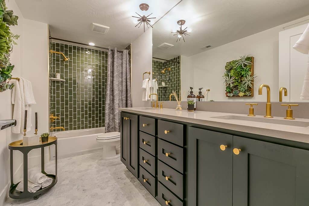 Le vert est le thème de cette belle salle de bain avec des robinets et des accessoires en laiton