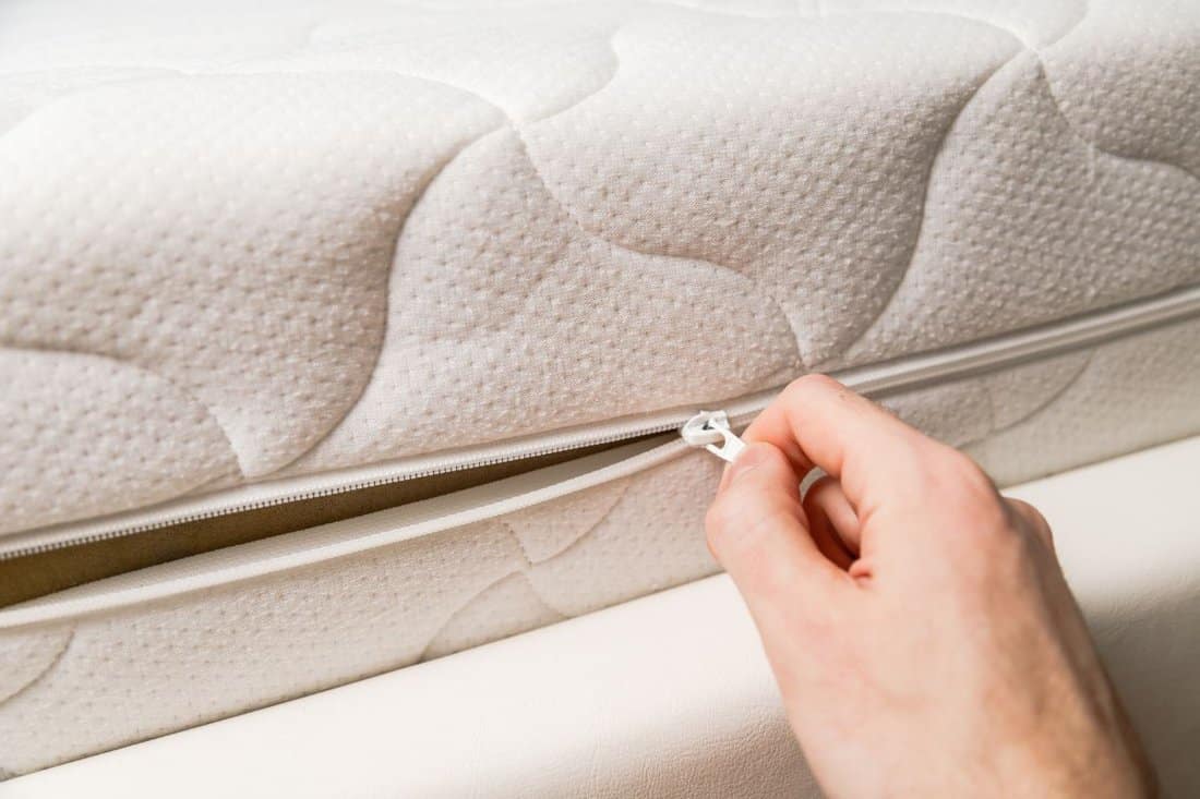 Hand opening cover of new mattress with zipper. Changing and washing cover. 