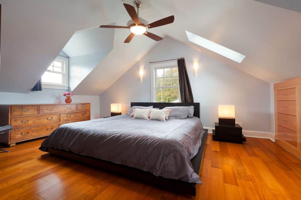Interior of a contemporary mansard bedroom with white painted walls and ceiling